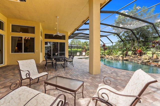 view of patio featuring a ceiling fan, glass enclosure, and an outdoor pool