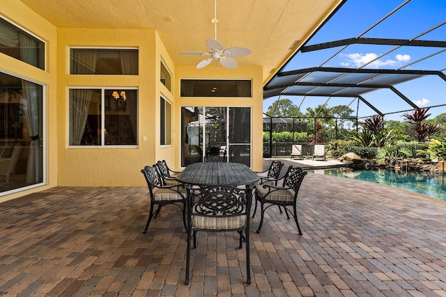 view of patio with a lanai, outdoor dining space, ceiling fan, and an outdoor pool