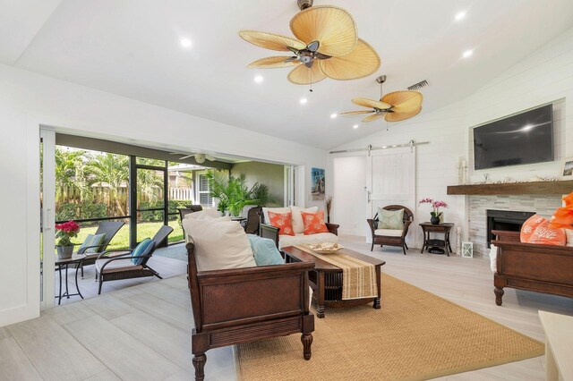 1155 Rainwood Cir, Palm Beach Gardens, FL 33410 - living area with ceiling fan, a barn door, a fireplace, vaulted ceiling, and visible vents