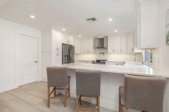 1155 Rainwood Cir, Palm Beach Gardens, FL 33410 - kitchen featuring visible vents, a sink, a peninsula, stainless steel appliances, and wall chimney exhaust hood