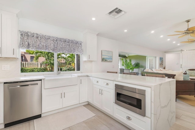1155 Rainwood Cir, Palm Beach Gardens, FL 33410 - kitchen with light stone counters, a sink, stainless steel appliances, a peninsula, and visible vents