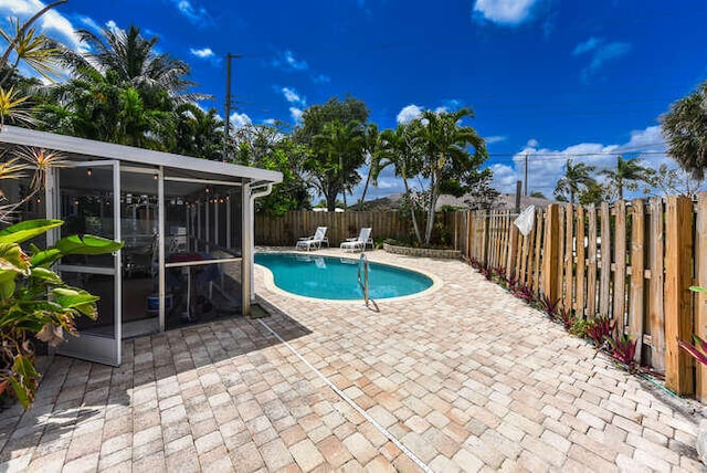 view of pool featuring a fenced backyard, a patio area, a fenced in pool, and a sunroom