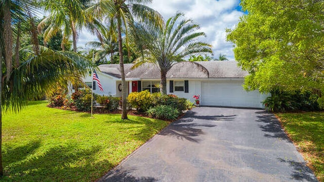 single story home featuring driveway, a front lawn, and a garage