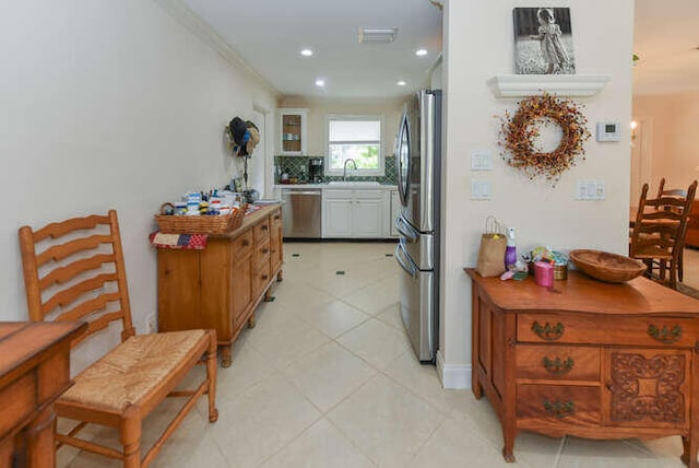 kitchen with recessed lighting, appliances with stainless steel finishes, a sink, light tile patterned flooring, and crown molding