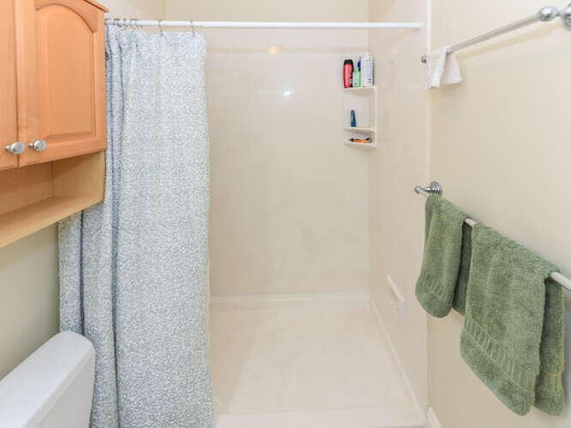bathroom with curtained shower and toilet