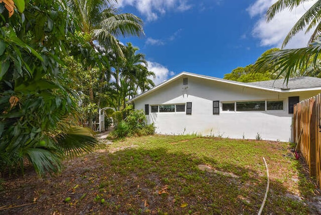view of side of property with stucco siding and fence