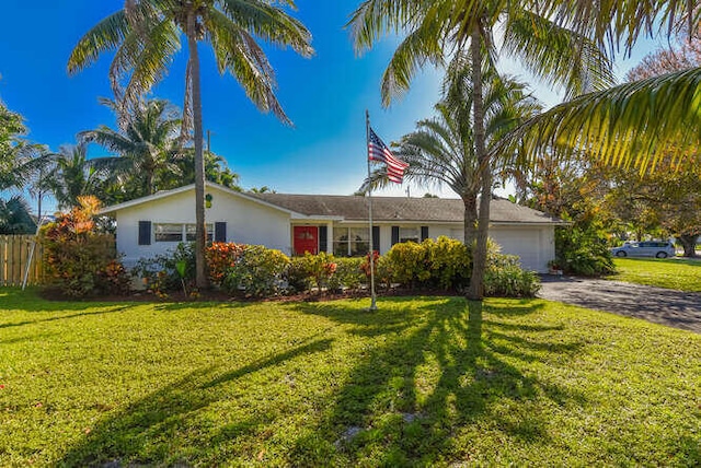 ranch-style house with a front yard, an attached garage, aphalt driveway, stucco siding, and fence