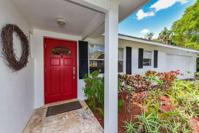 property entrance featuring stucco siding and an attached garage