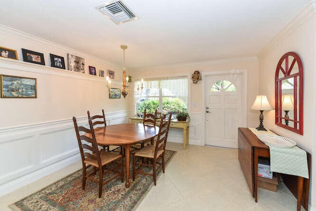 dining area with a notable chandelier, visible vents, a decorative wall, ornamental molding, and wainscoting