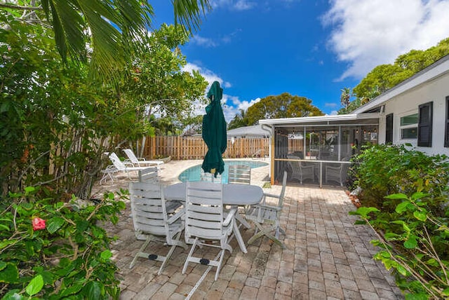 view of patio with a fenced in pool, a sunroom, outdoor dining space, and a fenced backyard