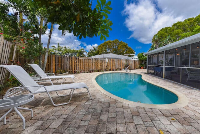 view of swimming pool featuring a fenced in pool, a fenced backyard, a sunroom, and a patio area