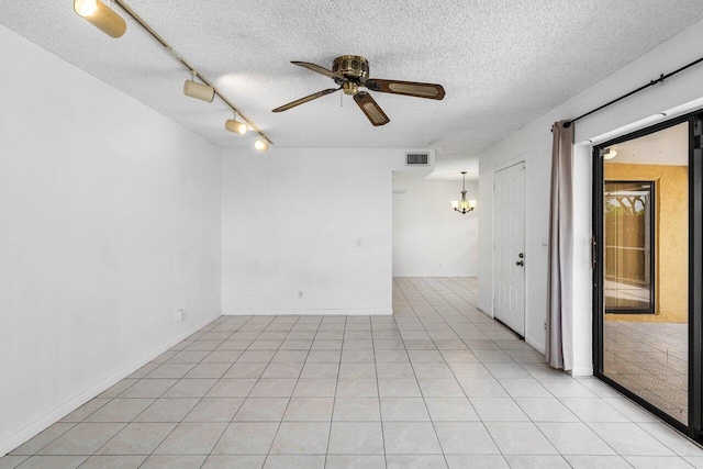 empty room featuring a textured ceiling, visible vents, rail lighting, and ceiling fan with notable chandelier