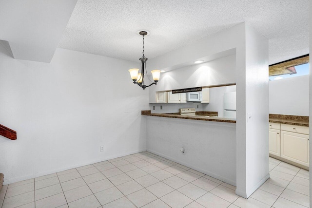 kitchen featuring dark countertops, a notable chandelier, white appliances, a textured ceiling, and pendant lighting