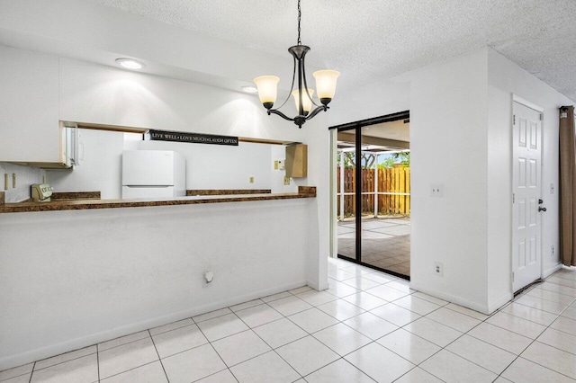 interior space with a textured ceiling, an inviting chandelier, and baseboards