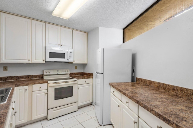 kitchen featuring white appliances, a textured ceiling, dark countertops, and light tile patterned floors