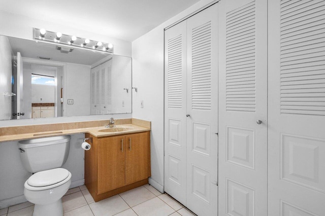half bathroom with vanity, toilet, tile patterned floors, and a closet