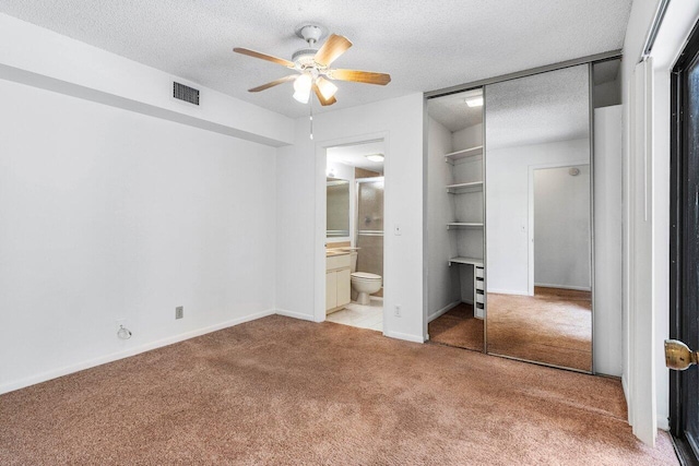 unfurnished bedroom with visible vents, a textured ceiling, baseboards, and light colored carpet