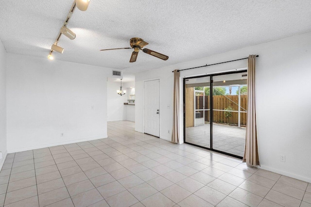 unfurnished room featuring a textured ceiling, visible vents, light tile patterned floors, track lighting, and ceiling fan with notable chandelier