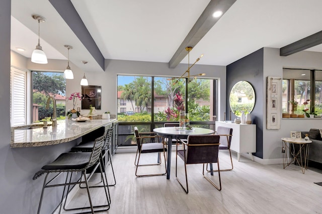 dining room with baseboards, beam ceiling, and light wood-type flooring