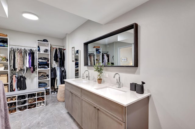 bathroom featuring double vanity, a spacious closet, marble finish floor, and a sink