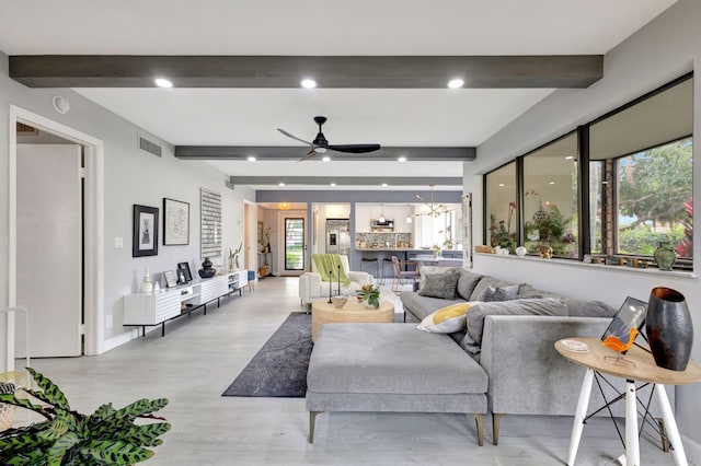 living room featuring beamed ceiling, light wood finished floors, a ceiling fan, and visible vents