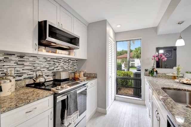 kitchen with decorative backsplash, white cabinets, stainless steel appliances, light wood-type flooring, and light stone countertops