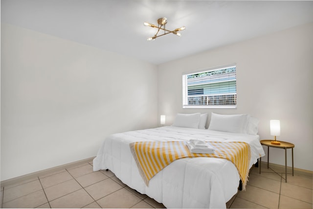 bedroom with a chandelier, light tile patterned flooring, and baseboards
