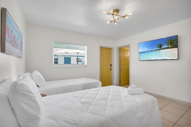 bedroom with a chandelier, light tile patterned floors, and baseboards