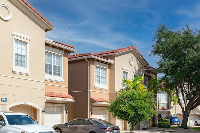 4891 Bonsai Cir Unit 105, Palm Beach Gardens, FL 33418 - exterior space featuring a tiled roof, stucco siding, and a garage