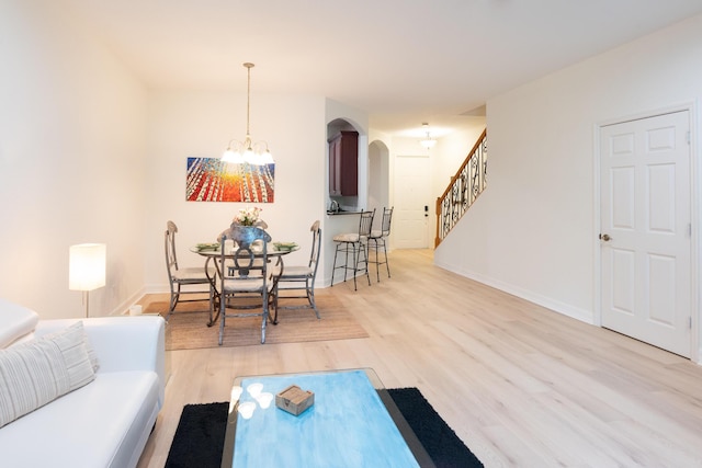 4891 Bonsai Cir Unit 105, Palm Beach Gardens, FL 33418 - living area featuring an inviting chandelier, light wood-style floors, arched walkways, baseboards, and stairway