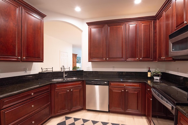 4891 Bonsai Cir Unit 105, Palm Beach Gardens, FL 33418 - kitchen with arched walkways, dark brown cabinets, a sink, dark stone countertops, and stainless steel appliances