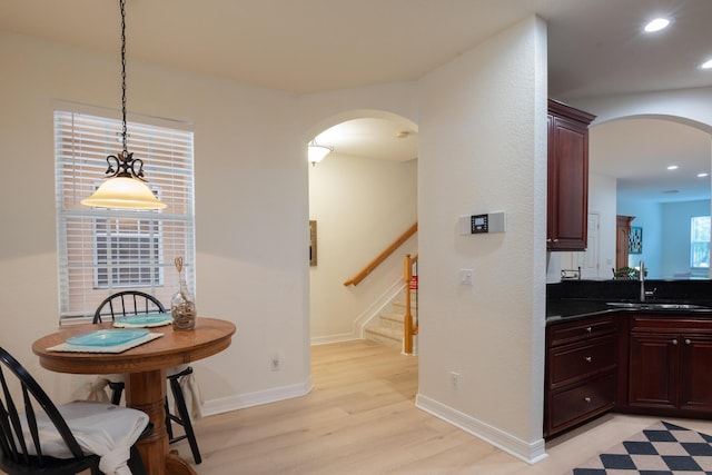 4891 Bonsai Cir Unit 105, Palm Beach Gardens, FL 33418 - kitchen with light wood-style floors, arched walkways, a sink, and dark countertops