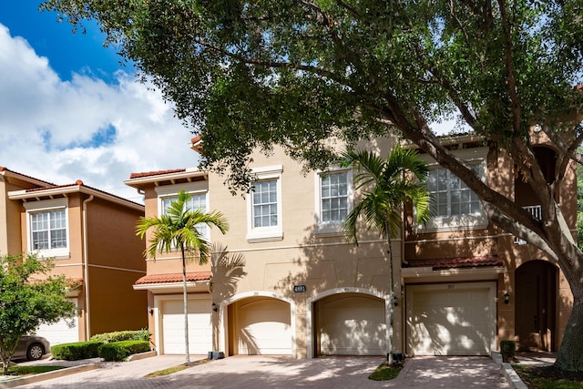 4891 Bonsai Cir Unit 105, Palm Beach Gardens, FL 33418 - view of front of house with stucco siding, an attached garage, driveway, and a tile roof