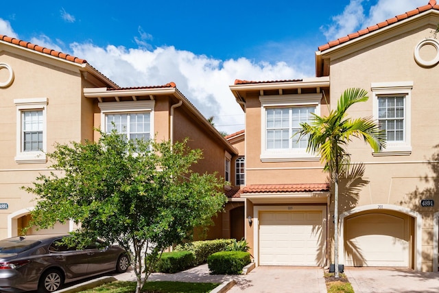 4891 Bonsai Cir Unit 105, Palm Beach Gardens, FL 33418 - view of front of house with a garage, stucco siding, a tiled roof, and driveway
