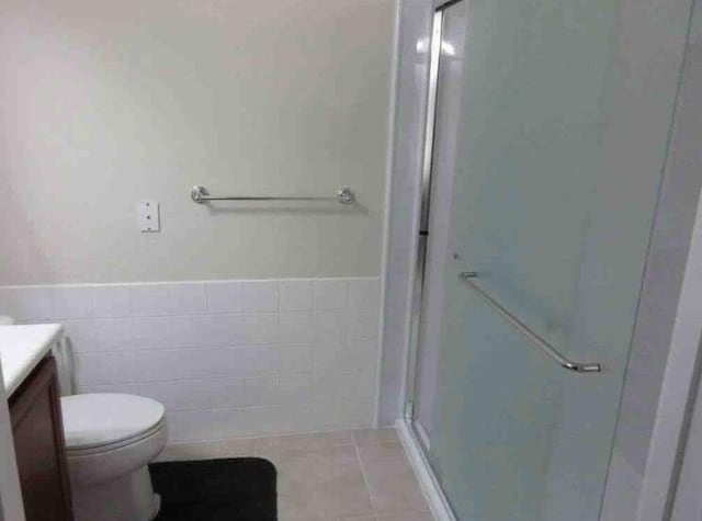 3531 Plume Way SE, Palm Bay, FL 32909 - bathroom featuring wainscoting, a stall shower, vanity, tile patterned floors, and toilet
