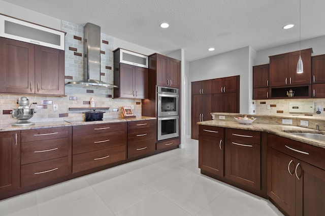 8881 Livingston Way, Boynton Beach, FL 33472 - kitchen with light stone countertops, stainless steel double oven, wall chimney exhaust hood, decorative light fixtures, and tasteful backsplash