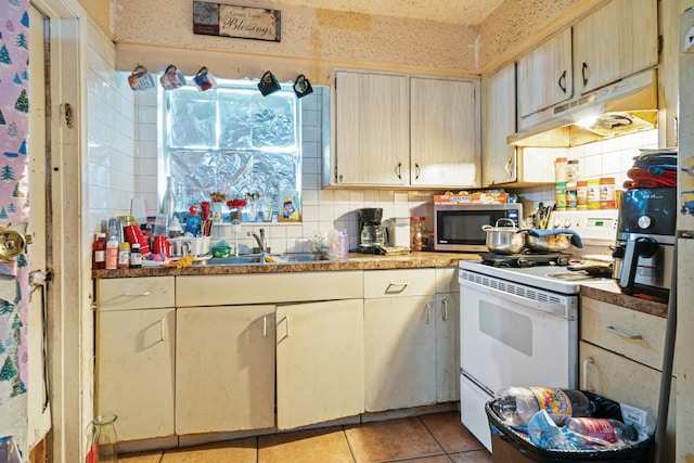 3208 Prince Dr, Lake Worth, FL 33461 - kitchen featuring under cabinet range hood, light tile patterned floors, a sink, stainless steel microwave, and white range with electric cooktop
