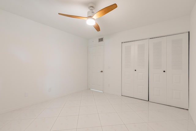 unfurnished bedroom with visible vents, light tile patterned floors, ceiling fan, and a closet
