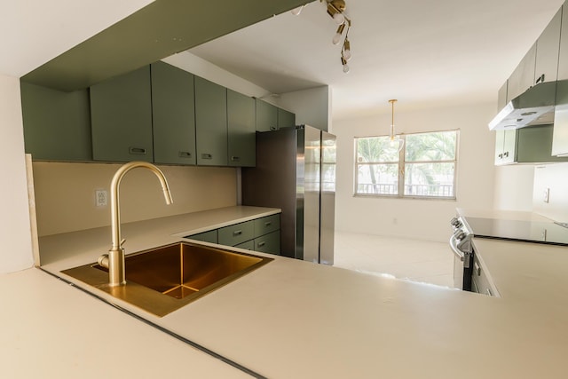 kitchen with a sink, under cabinet range hood, light countertops, green cabinetry, and appliances with stainless steel finishes