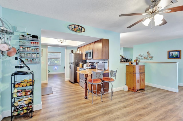 387 Yvonne Dr, West Palm Beach, FL 33406 - kitchen with appliances with stainless steel finishes, light wood-style flooring, baseboards, and a textured ceiling