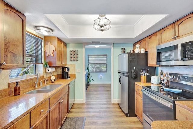 387 Yvonne Dr, West Palm Beach, FL 33406 - kitchen featuring stainless steel appliances, a sink, a tray ceiling, backsplash, and light wood-type flooring