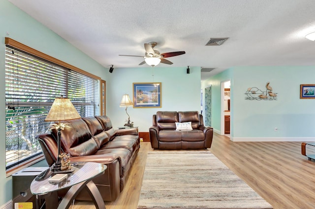 387 Yvonne Dr, West Palm Beach, FL 33406 - living room featuring light wood-style flooring, a textured ceiling, a ceiling fan, and baseboards