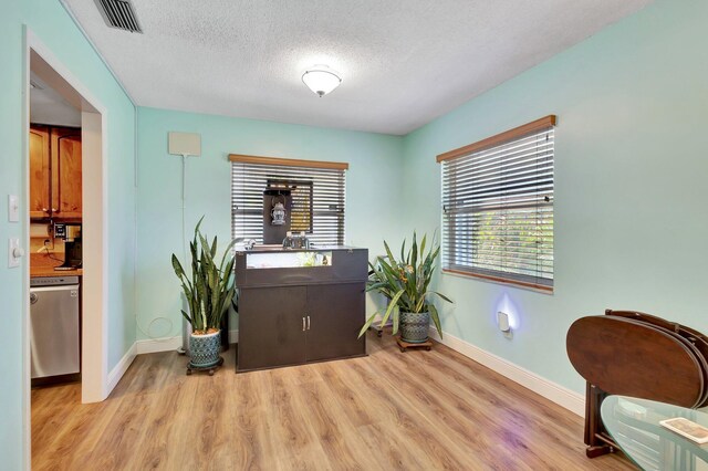 387 Yvonne Dr, West Palm Beach, FL 33406 - sitting room featuring light wood-type flooring, baseboards, and a textured ceiling