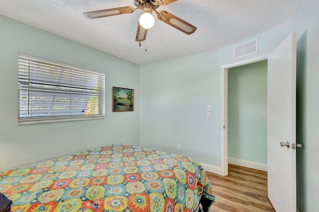 387 Yvonne Dr, West Palm Beach, FL 33406 - bedroom featuring light wood-style floors, a textured ceiling, ceiling fan, and baseboards