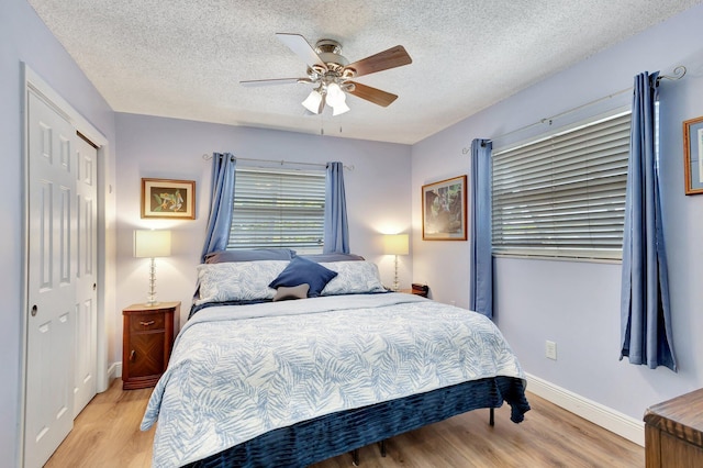 387 Yvonne Dr, West Palm Beach, FL 33406 - bedroom with light wood-style floors, a textured ceiling, a ceiling fan, baseboards, and a closet