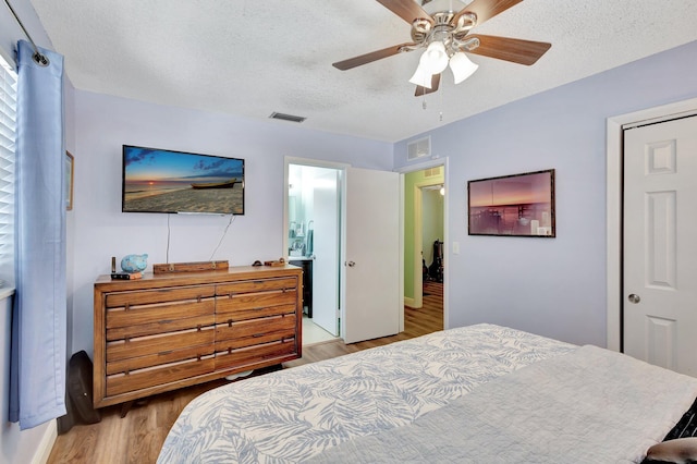 387 Yvonne Dr, West Palm Beach, FL 33406 - bedroom featuring light wood-style flooring, a textured ceiling, ceiling fan, and ensuite bath