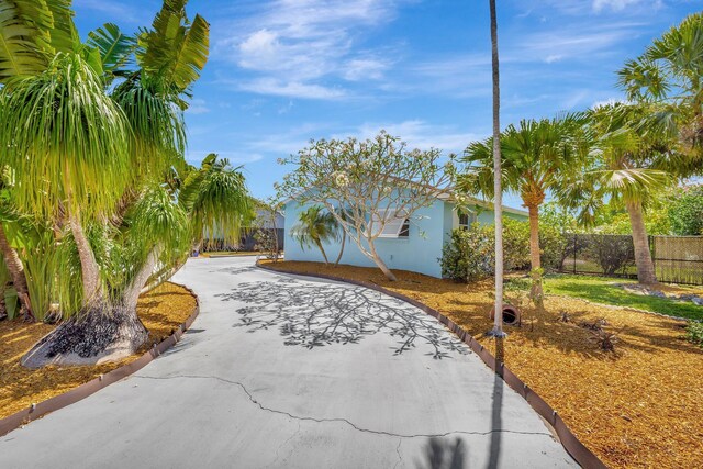 387 Yvonne Dr, West Palm Beach, FL 33406 - view of front facade with fence, curved driveway, and stucco siding