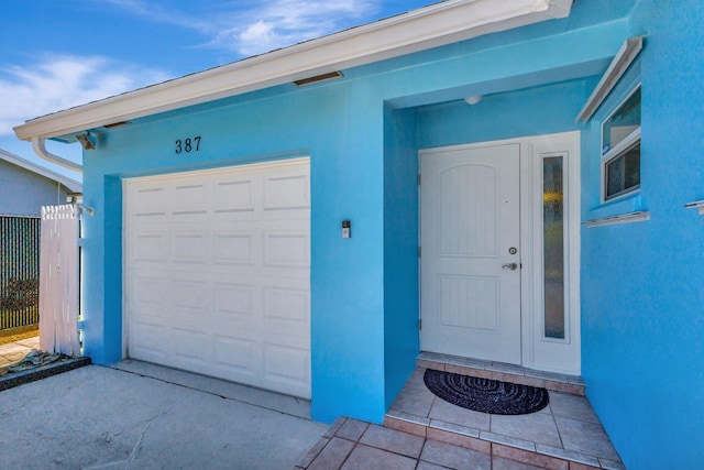 387 Yvonne Dr, West Palm Beach, FL 33406 - entrance to property featuring stucco siding, a garage, driveway, and fence