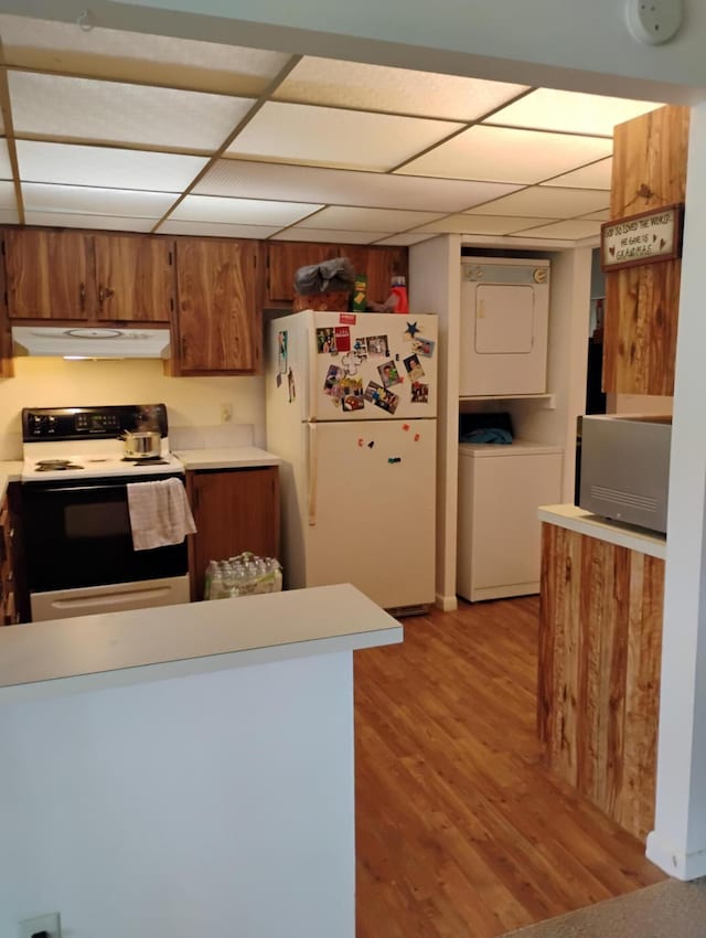 131 Lakes End Dr Unit D, Fort Pierce, FL 34982 - kitchen with electric stove, freestanding refrigerator, estacked washer and dryer, brown cabinetry, and under cabinet range hood