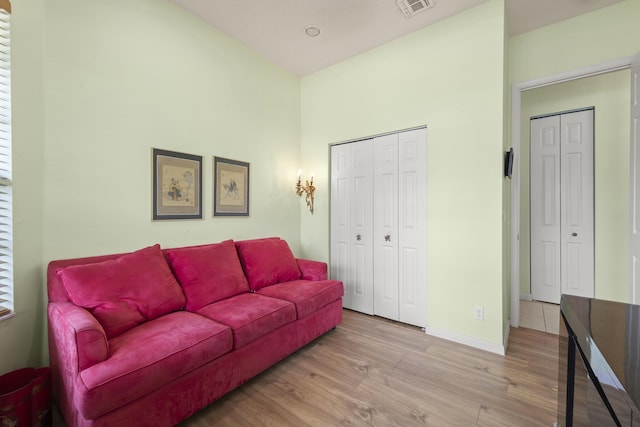 living area featuring baseboards, visible vents, wood finished floors, and a high ceiling
